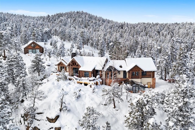 snowy aerial view featuring a view of trees and a mountain view