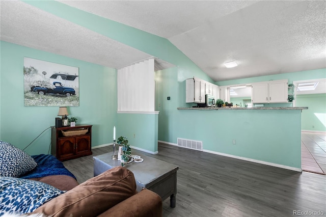 living area featuring lofted ceiling, visible vents, a textured ceiling, wood finished floors, and baseboards