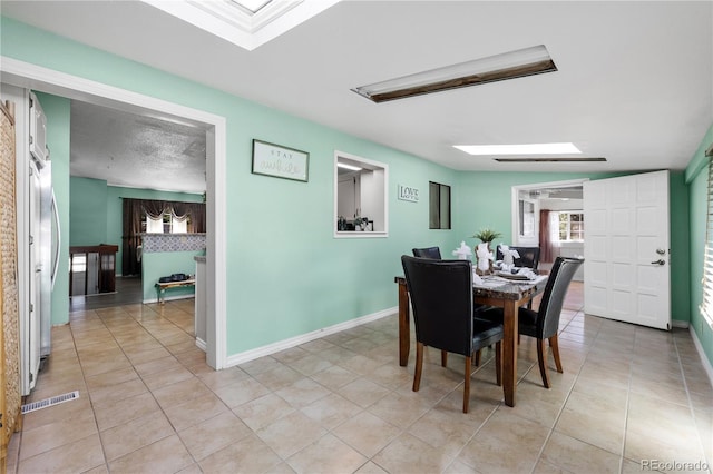 dining room with a skylight, baseboards, visible vents, and light tile patterned flooring