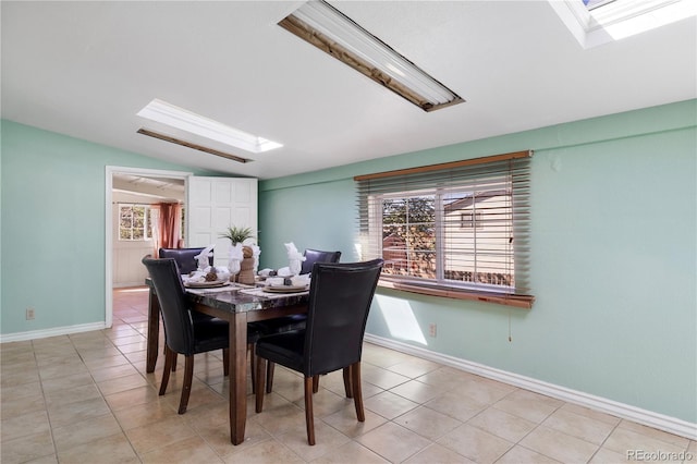 dining area featuring light tile patterned floors, vaulted ceiling with skylight, and baseboards