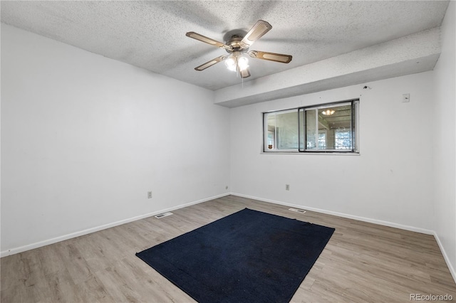 spare room with a ceiling fan, a textured ceiling, baseboards, and wood finished floors