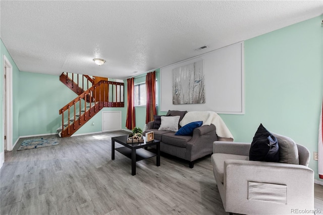 living area featuring stairs, visible vents, and wood finished floors