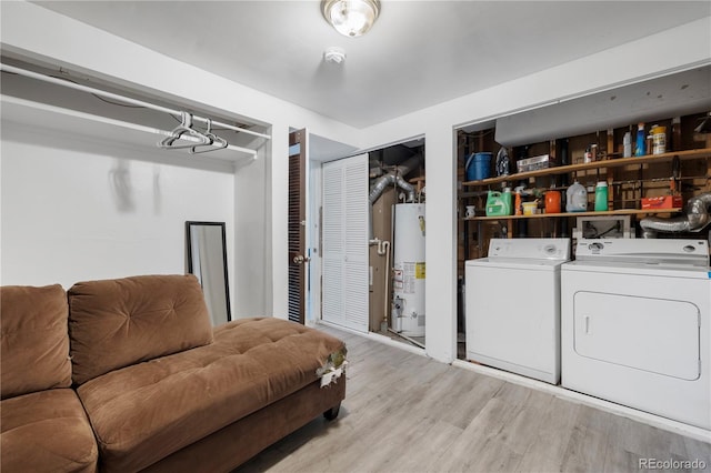 clothes washing area featuring water heater, laundry area, washer and clothes dryer, and wood finished floors