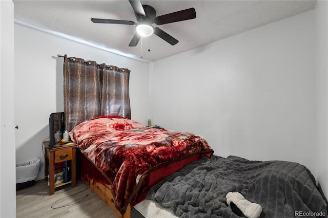 bedroom with a ceiling fan, a textured ceiling, and wood finished floors