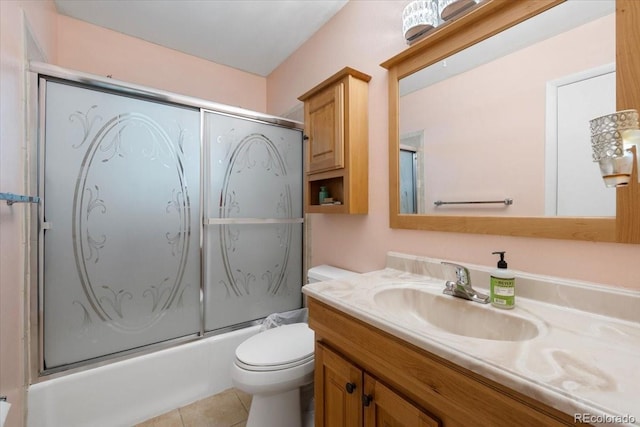 full bath with toilet, bath / shower combo with glass door, vanity, and tile patterned flooring