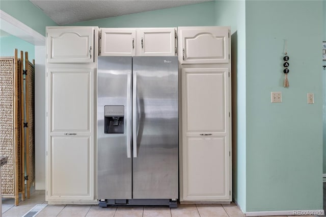 kitchen with stainless steel fridge with ice dispenser, vaulted ceiling, white cabinets, and light tile patterned flooring