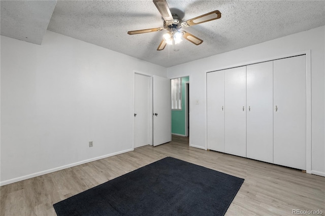 unfurnished bedroom featuring wood finished floors, a textured ceiling, baseboards, a ceiling fan, and a closet