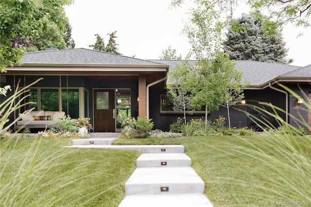 exterior space featuring a shingled roof and a front yard