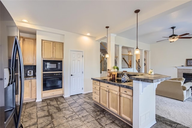 kitchen with decorative light fixtures, a fireplace, black appliances, a breakfast bar, and light brown cabinetry