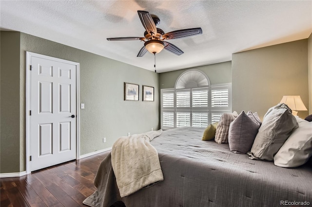 bedroom with dark wood-type flooring, ceiling fan, and a textured ceiling