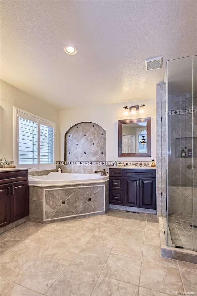 bathroom with a textured ceiling, separate shower and tub, and vanity