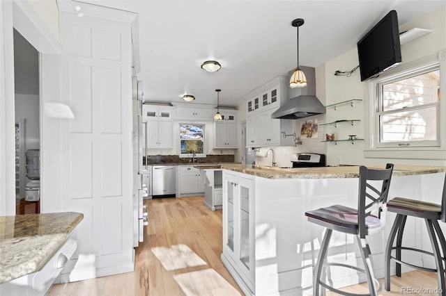 kitchen with pendant lighting, white cabinets, a kitchen breakfast bar, light hardwood / wood-style flooring, and appliances with stainless steel finishes