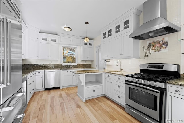 kitchen featuring white cabinets, wall chimney exhaust hood, light hardwood / wood-style floors, and appliances with stainless steel finishes