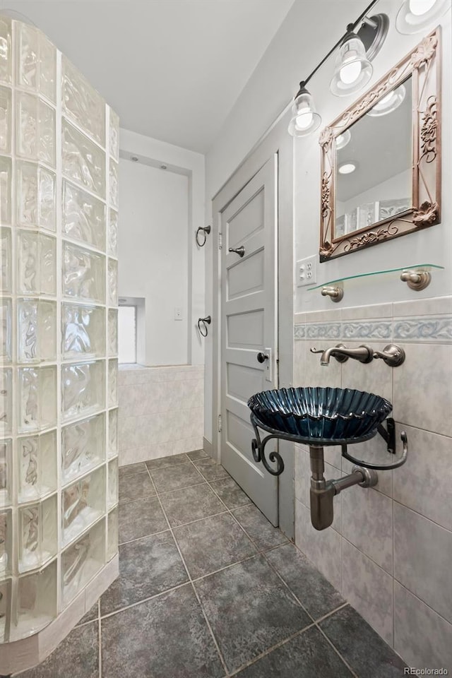 bathroom with tile patterned flooring, sink, a shower, and tile walls