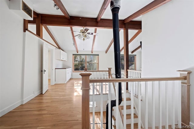 hall with light wood-type flooring and vaulted ceiling with beams