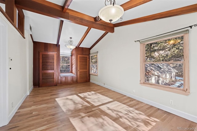 unfurnished living room with vaulted ceiling with beams and light hardwood / wood-style floors