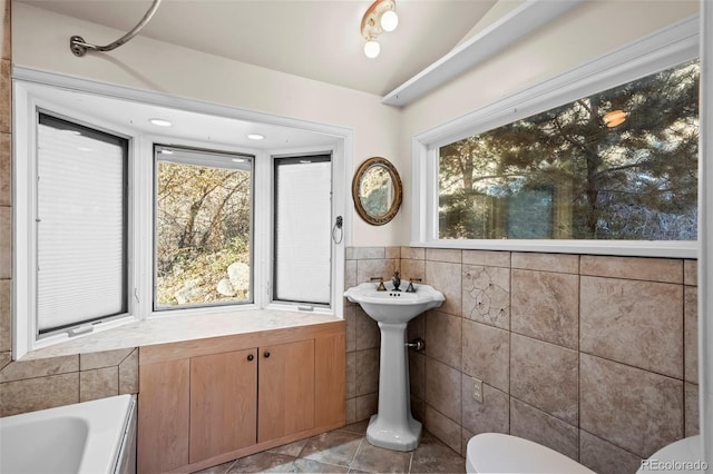 bathroom with tile patterned flooring, plenty of natural light, and tile walls