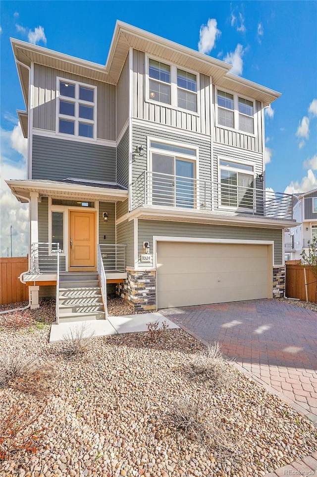 10124 Xanadu St, Commerce City, CO 80022 - view of front of home with board and batten siding, stone siding, fence, an attached garage, and driveway