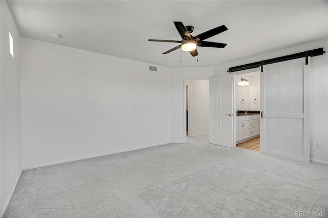10124 Xanadu St, Commerce City, CO 80022 - unfurnished bedroom with light colored carpet, ensuite bath, visible vents, a barn door, and baseboards