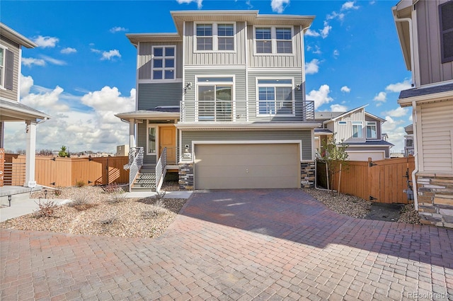 10124 Xanadu St, Commerce City, CO 80022 - view of front of house with an attached garage, stone siding, fence, and decorative driveway