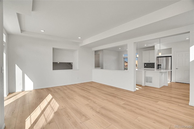 10124 Xanadu St, Commerce City, CO 80022 - unfurnished living room with light wood-style flooring, baseboards, visible vents, and recessed lighting