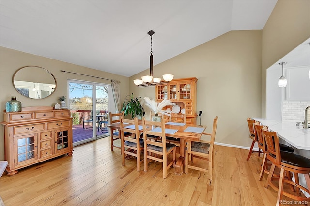 dining area with an inviting chandelier, lofted ceiling, baseboards, and light wood-type flooring