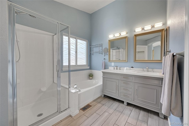 bathroom with wood finish floors, a stall shower, visible vents, and a sink