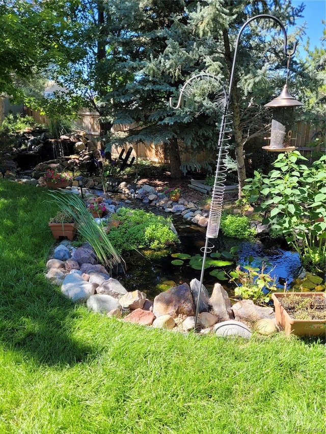 view of yard with a garden pond and fence