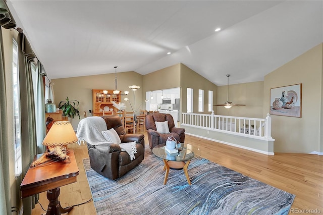 living area with a healthy amount of sunlight, baseboards, lofted ceiling, and wood finished floors