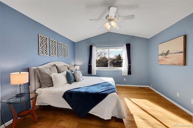 bedroom featuring baseboards, lofted ceiling, wood finished floors, and a ceiling fan