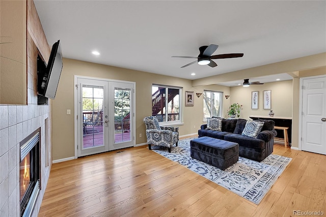 living area with baseboards, light wood finished floors, recessed lighting, french doors, and a glass covered fireplace