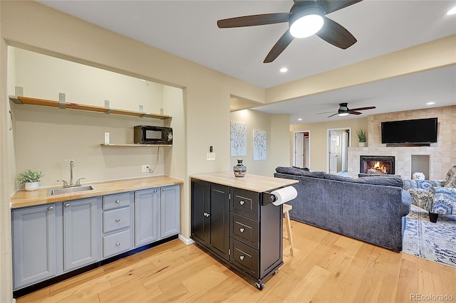 kitchen featuring a sink, light wood-type flooring, butcher block counters, and black microwave