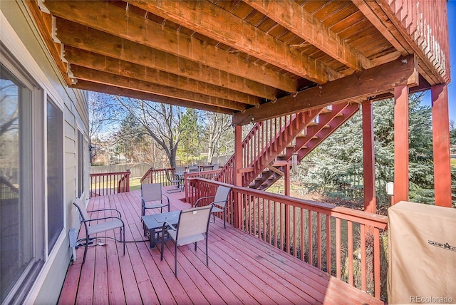 wooden terrace featuring outdoor dining area, stairs, and fence