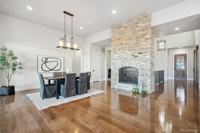 dining space with wood-type flooring and a brick fireplace