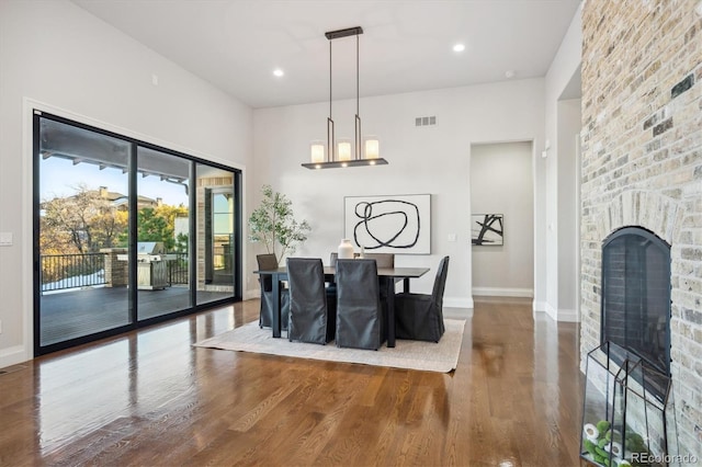 dining space featuring an inviting chandelier, hardwood / wood-style flooring, and a brick fireplace