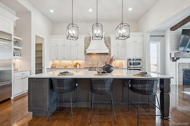 kitchen featuring a large island with sink, dark hardwood / wood-style floors, and appliances with stainless steel finishes