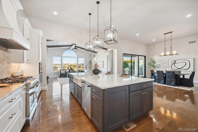 kitchen with appliances with stainless steel finishes, premium range hood, white cabinetry, and pendant lighting