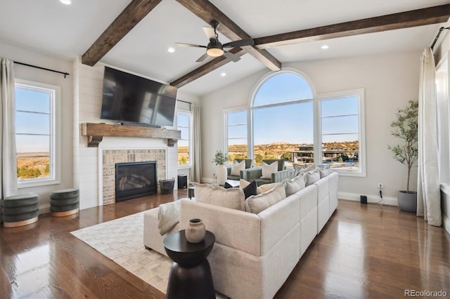 living room featuring vaulted ceiling with beams, dark hardwood / wood-style floors, a brick fireplace, and a healthy amount of sunlight