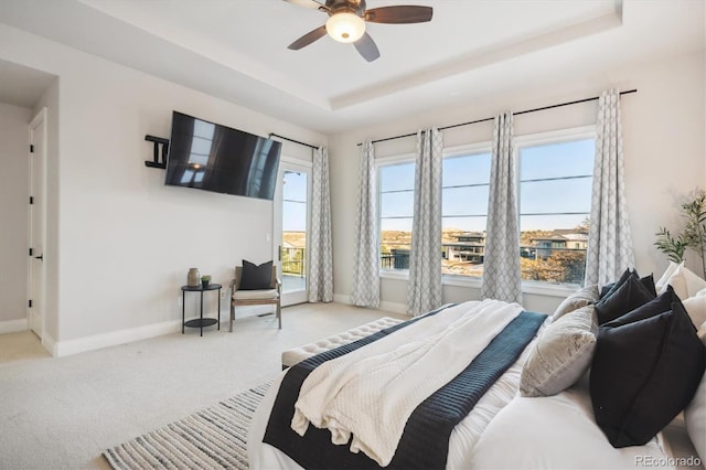 carpeted bedroom featuring a raised ceiling and ceiling fan