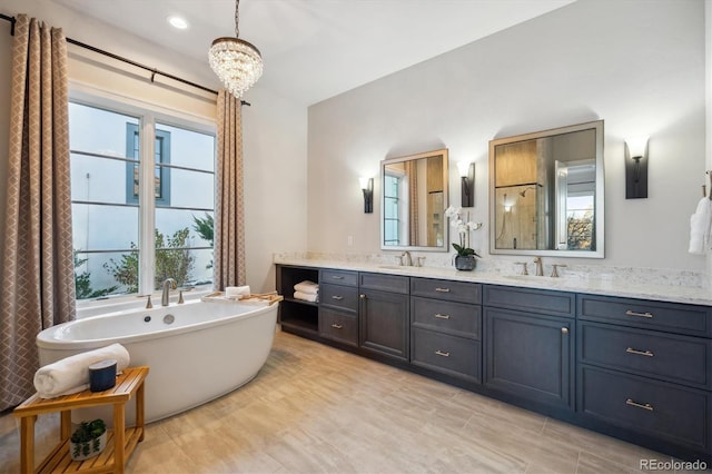 bathroom featuring a wealth of natural light, a washtub, vanity, and a chandelier