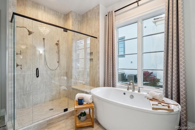 bathroom with shower with separate bathtub and a wealth of natural light