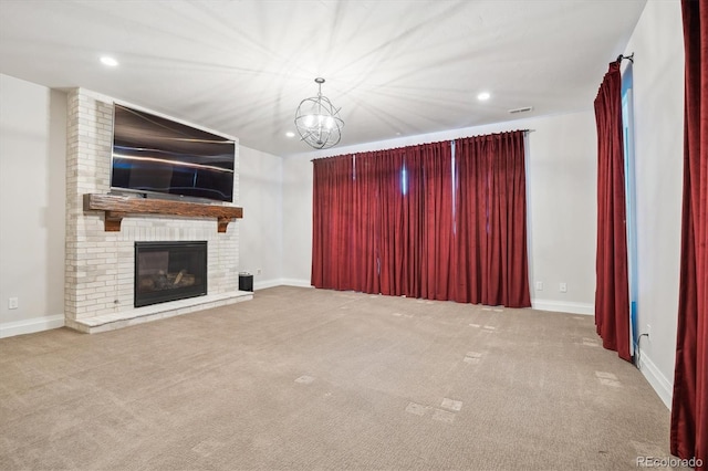 unfurnished living room with carpet flooring, an inviting chandelier, and a brick fireplace