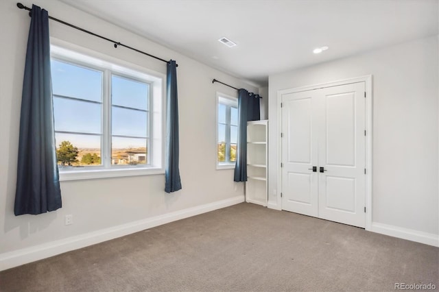 unfurnished bedroom with carpet flooring, a closet, and multiple windows