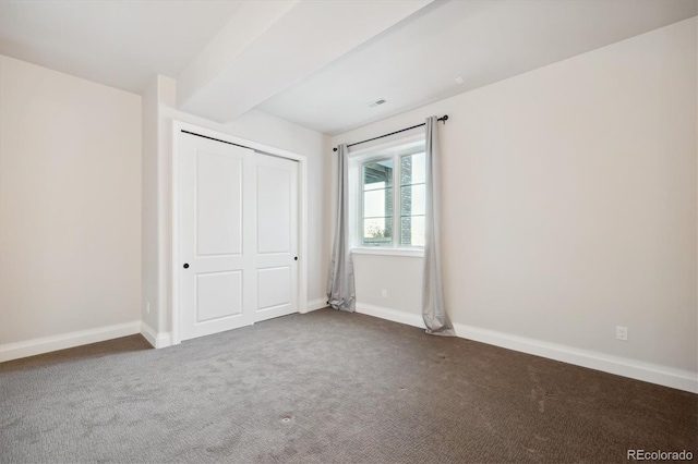 unfurnished bedroom with dark carpet and a closet