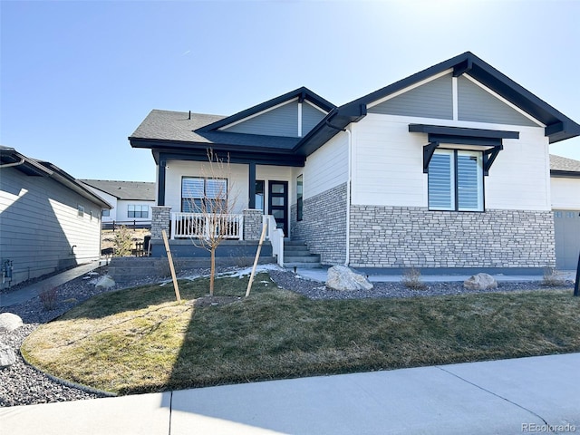 view of front of home with stone siding, a front lawn, and a porch