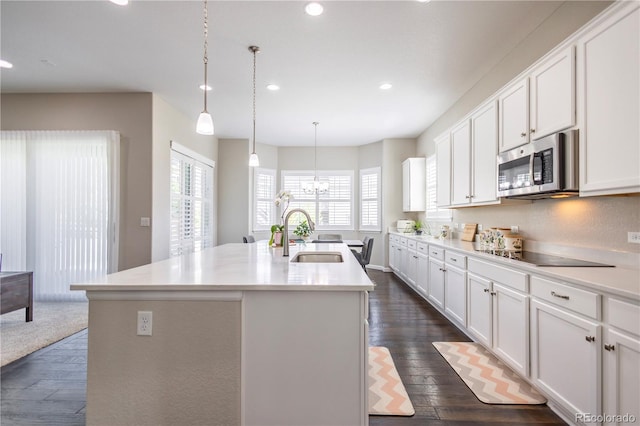 26722 E Peakview Pl, Aurora, CO 80016 - kitchen featuring stainless steel microwave, black electric stovetop, dark wood-style floors, recessed lighting, and a center island with sink