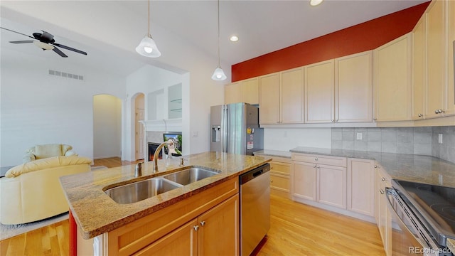 6187 Reed Way, Arvada, CO 80003 - kitchen featuring stainless steel appliances, open floor plan, ceiling fan, an island with sink, and arched walkways