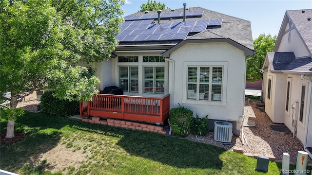 6187 Reed Way, Arvada, CO 80003 - rear view of property featuring stucco siding, solar panels, a wooden deck, and a lawn