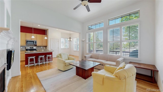 6187 Reed Way, Arvada, CO 80003 - living area featuring a fireplace, healthy amount of natural light, a ceiling fan, and light wood finished floors