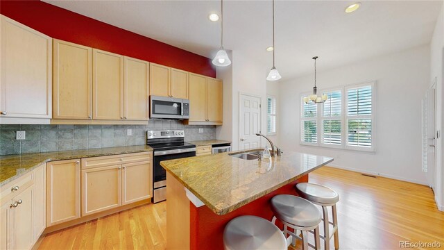 6187 Reed Way, Arvada, CO 80003 - kitchen with appliances with stainless steel finishes, light wood finished floors, decorative backsplash, light brown cabinetry, and recessed lighting